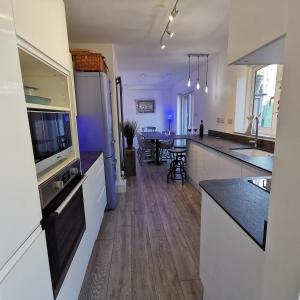 a kitchen with white cabinets and black counter tops at AnchorageWells Holiday Cottage and King Ensuites Room Only in Wells next the Sea