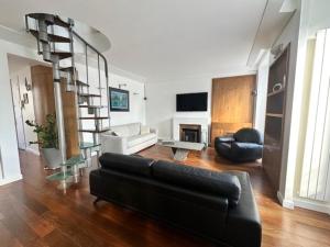 a living room with a black couch and a spiral staircase at Magnifique appartement Paris proche Arc Triomphe in Paris