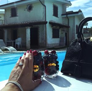 uma mulher segurando um copo de uvas em frente a uma piscina em Gold Luxury House em Anzio
