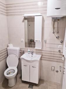 a white bathroom with a toilet and a sink at Apartman Mirabell, Doboj in Doboj