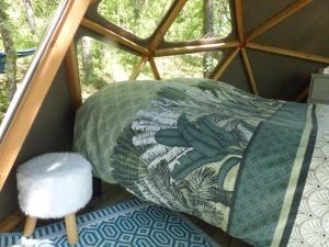 Cette chambre comprend un lit, un oreiller et une fenêtre. dans l'établissement Dôme géodésique au cœur de la forêt, à Montignac