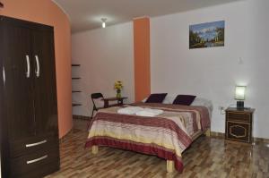 a bedroom with a bed and a cabinet and a table at Hostal Luren in Nazca