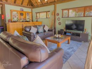 a living room with leather furniture and a flat screen tv at Hornbill House @ Zebula in Mabula