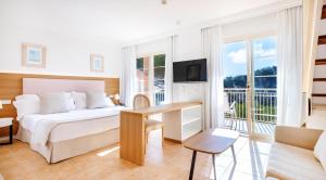 Schlafzimmer mit einem Bett, einem Schreibtisch und einem TV in der Unterkunft VIVA Cala Mesquida Suites & Spa Adults Only 16 in Cala Mesquida