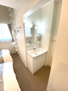 a white bathroom with a sink and a mirror at GuestHouseえにし in Nishi-kujō-Toriiguchichō