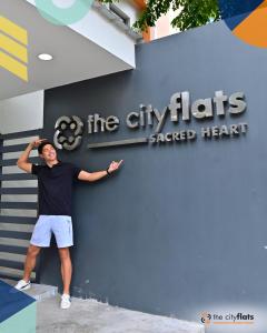 マニラにあるThe City Flats Sacred Heartの建物の前に立っている男性