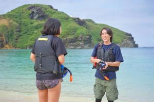 two people standing on the beach with the water at 与那国島ホテル むんぶステイ 比川浜 in Sonai