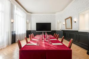 a room with a long table with chairs and a television at Hôtel de la Poste in Beaune