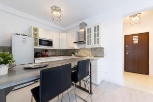 a kitchen with white cabinets and black chairs at Smile Apartments in Bucharest