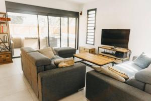 un salon avec deux canapés et une télévision à écran plat dans l'établissement Villa JoCeline - 4ch-4sdb - piscine chauffée - proche plage, à Saint-Paul