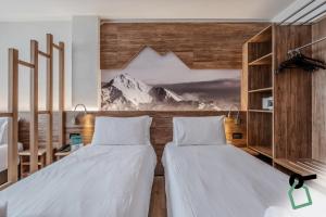 two beds in a room with a mountain mural at HOTIDAY Chalet Sestriere Vialattea in Sestriere
