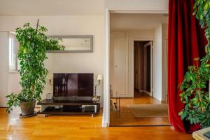 a living room with a flat screen tv and plants at Beautiful quiet apartment with views of Paris in Saint-Denis