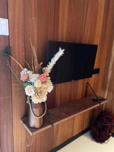 a vase of flowers on a shelf next to a tv at Ben's Cabine in Bodegraven