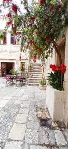a courtyard with a tree with red flowers and tables at Palace Derossi II in Trogir