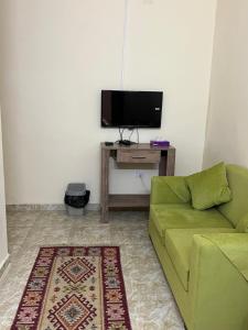 ein Wohnzimmer mit einem grünen Sofa und einem TV in der Unterkunft منتجع وفندق جدارا Jadara Resort & Hotel in Um Qeis