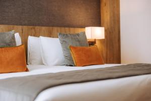 una camera da letto con un letto con cuscini arancioni e grigi di Valtur Cervinia Cristallo Ski Resort a Breuil-Cervinia