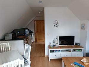 a living room with a table and a tv at Die Blaue Lagune, Hinter Den Dünen in Prerow