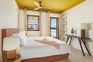 Teresa Spetses في سبيتسيس: غرفة نوم مع سرير مع مروحة سقف ونافذة