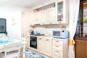 a kitchen with white cabinets and a microwave at 5 minuti dal Mare Casa Elegante con AC e WiFi in Valledoria