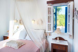 a bedroom with a canopy bed and a window at Sunrock Suites - Villa Jasmine in Stelida