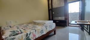 um quarto com uma cama, uma mesa e uma janela em HOTEL ARCHANA PALACE HAMPI em Hampi