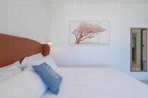 a bedroom with a white bed with blue pillows at Dimore delle Zagare Molo in Syracuse