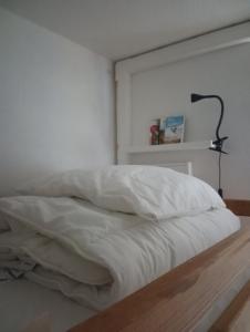Chamrousse - Résidence Eterlou في شامروس: سرير مع شراشف بيضاء ومصباح في الغرفة