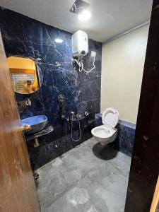 a bathroom with a toilet and a sink and a mirror at Hotel Paramount Villa in Gandhinagar