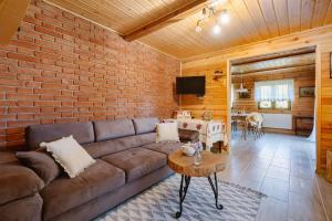 a living room with a couch and a brick wall at Podlaska chata otoczona ciszą. Na wyłączność in Kleniki