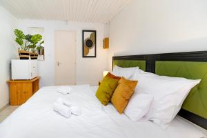 una camera da letto con un letto bianco con cuscini gialli e bianchi di Hagyma Panzió a Makó
