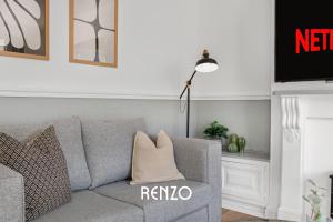 a living room with a gray couch with a pillow at Vibrant and Cosy 3-Bed Home in Nottingham by Renzo, Perfect for Contractors, Free Parking! in Beeston