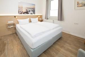 a large white bed in a room with a window at Haus Menno Janssen - Doppelzimmer in Norderney