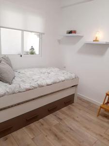 Ce lit se trouve dans un dortoir blanc doté d'une fenêtre. dans l'établissement Confortable apartamento en Elche, à Elche