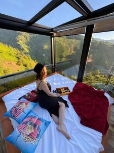 a woman sitting on a bed in a room with a view at Northland Bungalows in Çayırdüzü
