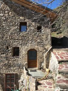 - un bâtiment en pierre avec une porte en bois dans l'établissement La Fenière, à Roubion