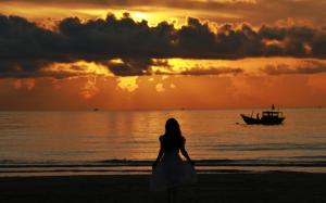 Una donna in piedi sulla spiaggia con una barca in acqua di iSea by the sea a Ninh Hòa