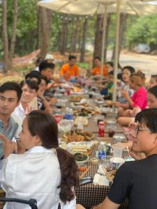 a group of people sitting at a long table eating food at Đồi Gió Hú Homestay & Coffee - Măng Đen in Kon Tum