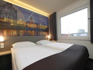 een slaapkamer met een groot bed en een groot raam bij B&B Hotel Berlin City-West in Berlijn