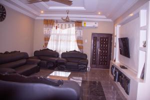 a living room with leather couches and a television at Maakyere Apartments in Kintampo