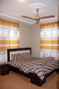 a bedroom with a bed with curtains and a fan at Maakyere Apartments in Kintampo