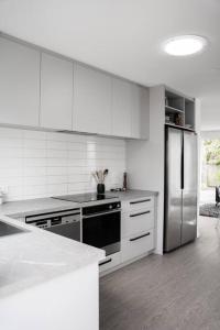 a kitchen with white cabinets and a stainless steel refrigerator at Restful stay on Geraldine Street Suburban Beauty in Christchurch