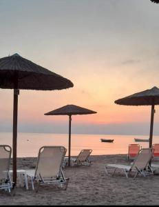 a group of chairs and umbrellas on a beach at Nikolas Beach House in Mesongi