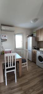 uma cozinha com uma mesa, 2 cadeiras e um frigorífico em Apartmani Elena em Kostići