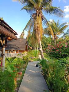 un camino que conduce a una casa con palmeras y flores en Bintang Tiga Bungalows Gili Air en Gili Air