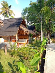 una casa con techo negro y algunas palmeras en Bintang Tiga Bungalows Gili Air en Gili Air
