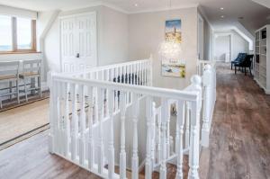 a white staircase in a living room with a chandelier at Highfield - 5 Bedroom Holiday Home - Pembroke Dock in Pembroke Dock