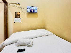 een slaapkamer met een bed en een tv aan de muur bij Penginapan Dvn & Tmy 01 RedPartner in Palembang