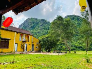 ein gelbes Haus auf einem Feld mit Bergen im Hintergrund in der Unterkunft Huy-Mountainside Homestay in Phong Nha