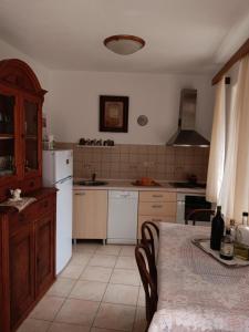 a kitchen with a table and a white refrigerator at Guest House Lucijo in Vrboska