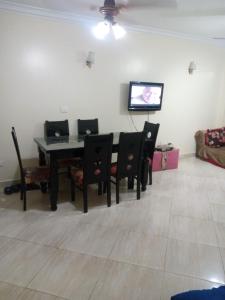 ein Esszimmer mit einem Tisch und Stühlen sowie einem TV in der Unterkunft Qronful in Kairo